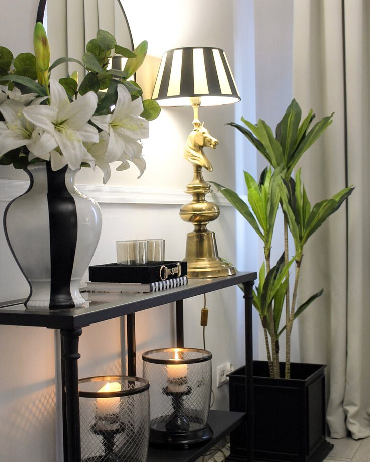 two vases with flowers and candles on a shelf in front of a mirror next to a lamp