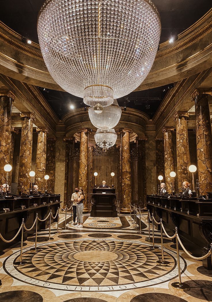 two people standing in front of a chandelier at the entrance to a lobby