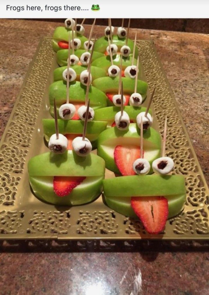 some green apples with googly eyes and strawberries on them are ready to be eaten