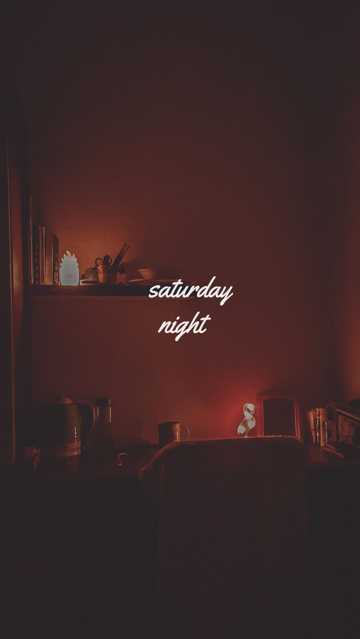 there is a neon sign that says saturday night on the wall next to bookshelves