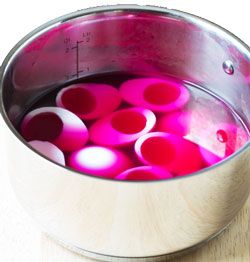 two metal pans filled with red liquid on top of a wooden table next to each other