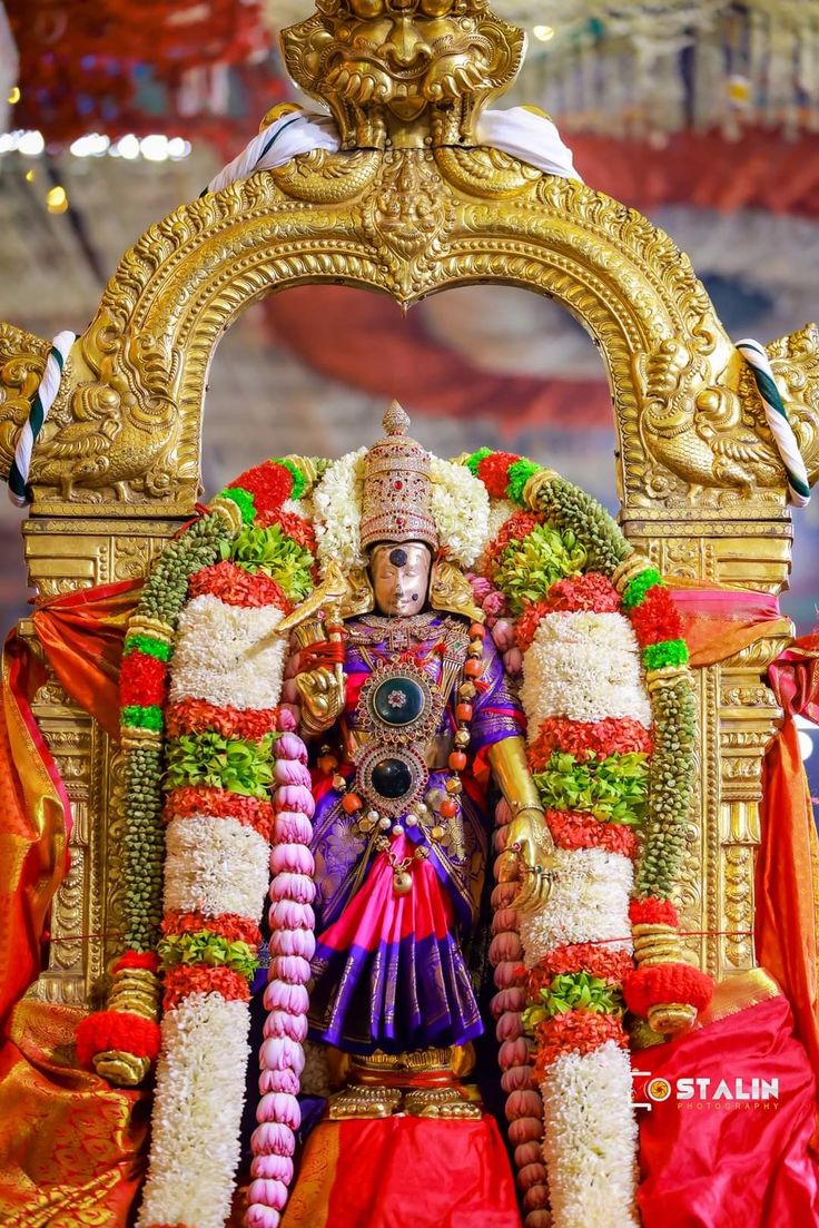 an idol is displayed in the middle of a stage with flowers and garlands on it