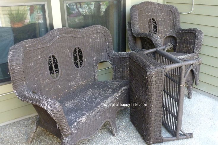 two wicker chairs sitting next to each other in front of a house with windows