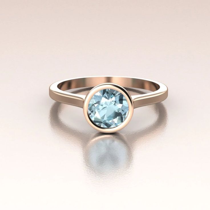 14K Rose Gold modern engagement ring. This ring has a delicate cathedral shank and bezel set round Aquamarine. The center stone is 6mm (total weight around 1ct, color may vary due to the nature of this stone) bezel set. There is nothing better for the modern bride! Simple, elegant and beautiful.We only work with environment friendly precious metals and conflict free stones. All our jewelry is made in SOLID gold, no gold-filled or gold plated jewelry. The process we use to fabricate our jewelry i Modern Rose Gold Rings With Bezel Setting, Modern 14k Gold Topaz Ring With Bezel Setting, Modern 14k Gold Bezel Set Topaz Ring, Modern Round Cut Birthstone Ring With Bezel Setting, Modern Bezel Set Birthstone Promise Ring, Modern Birthstone Ring With Bezel Setting For Promise, Modern Birthstone Ring With Bezel Setting, Modern Topaz Promise Ring With Bezel Setting, Modern Round Birthstone Ring With Tension Setting