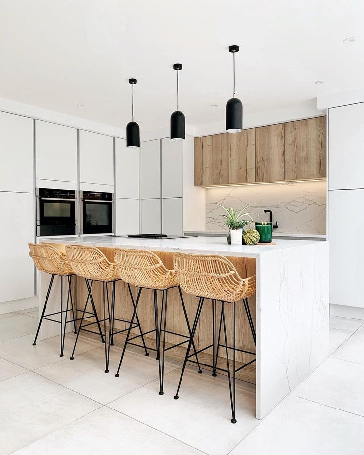 an island in the middle of a kitchen with stools next to it and potted plants on top