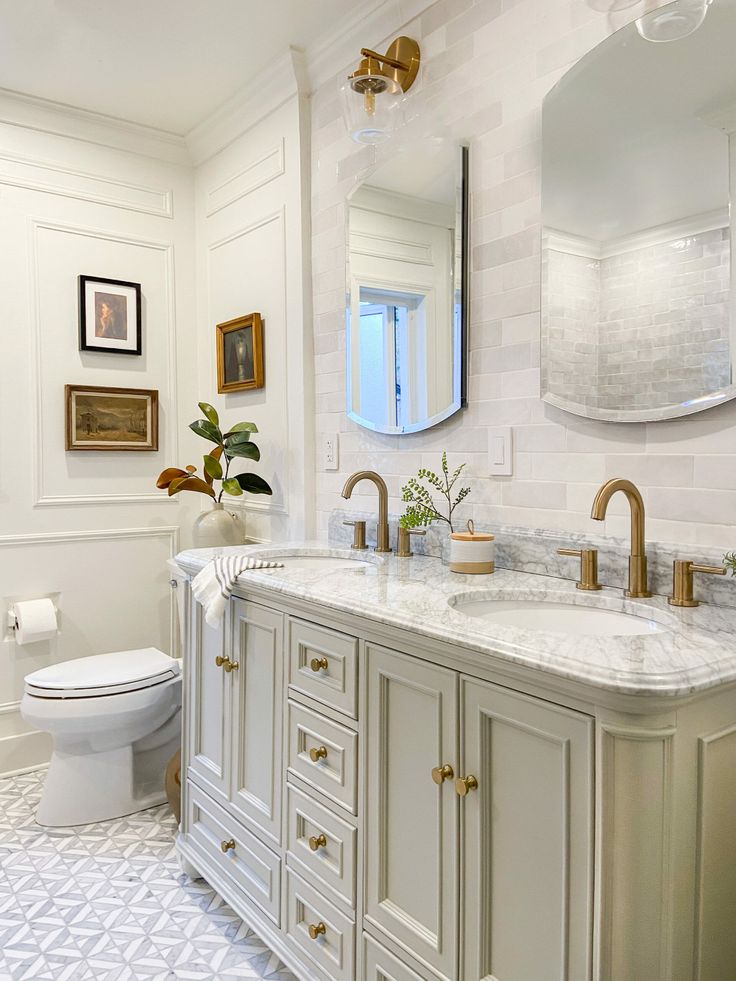 a bathroom with two sinks, a toilet and a large mirror above the sink in it