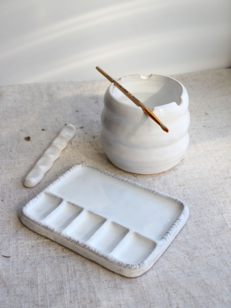 a white container with a wooden stick sticking out of it next to an empty tray