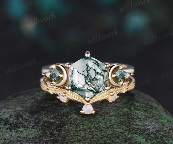 a green and white stone ring on top of a mossy rock with gold accents