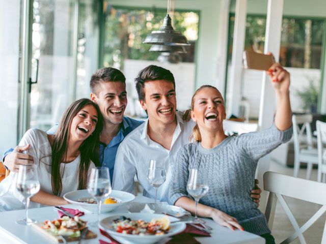 a group of people sitting at a table with food and drinks in front of them