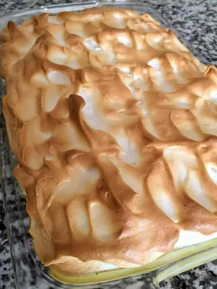 a cake that is sitting on top of a glass pan with frosting in it