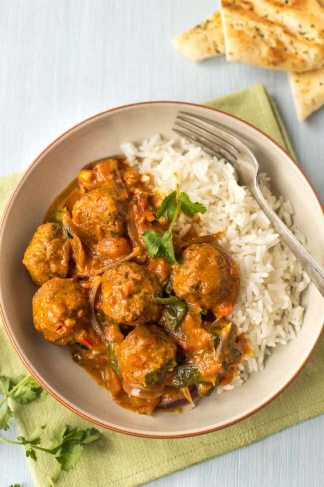 a white plate topped with meatballs and rice next to crackers on a table