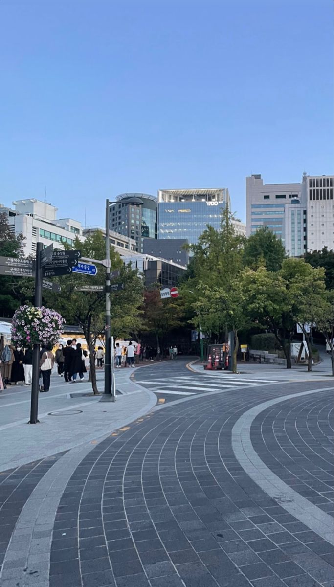 people are walking down the street in front of tall buildings