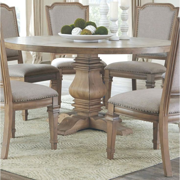 a dining room table with chairs and a bowl of fruit on top of the table