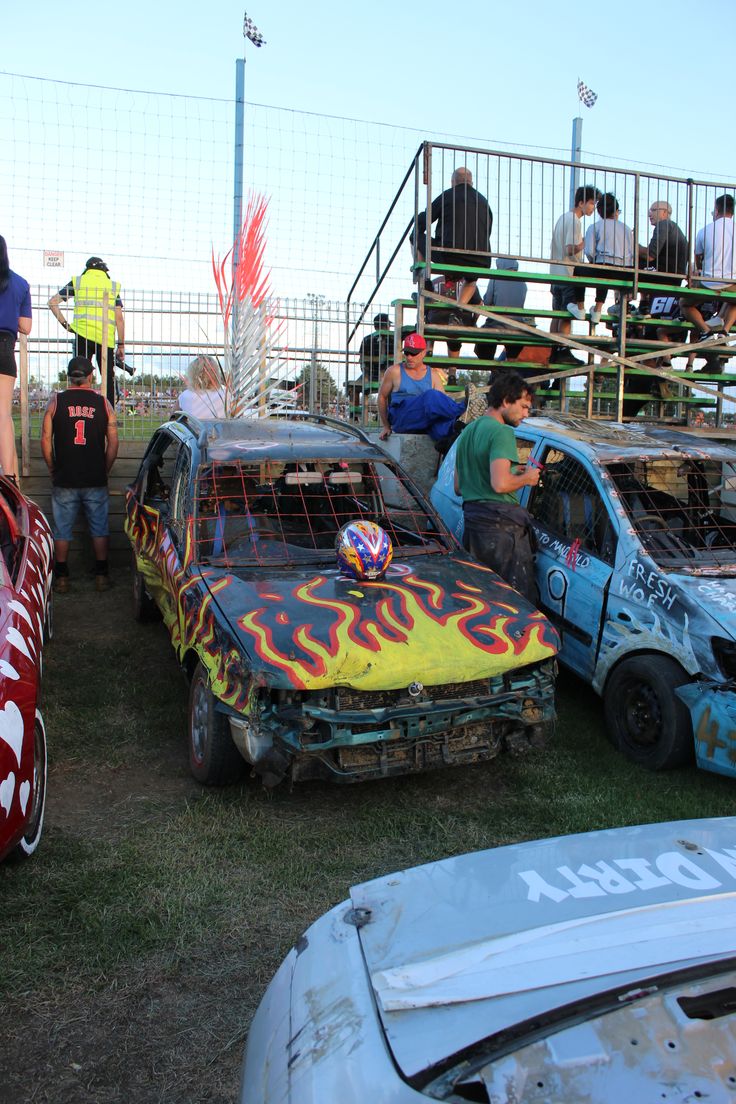 several cars with flames painted on them are parked in the grass at a race track