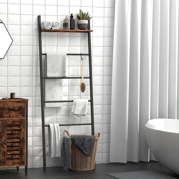 a bathroom with white tile walls and flooring next to a wooden shelf filled with towels