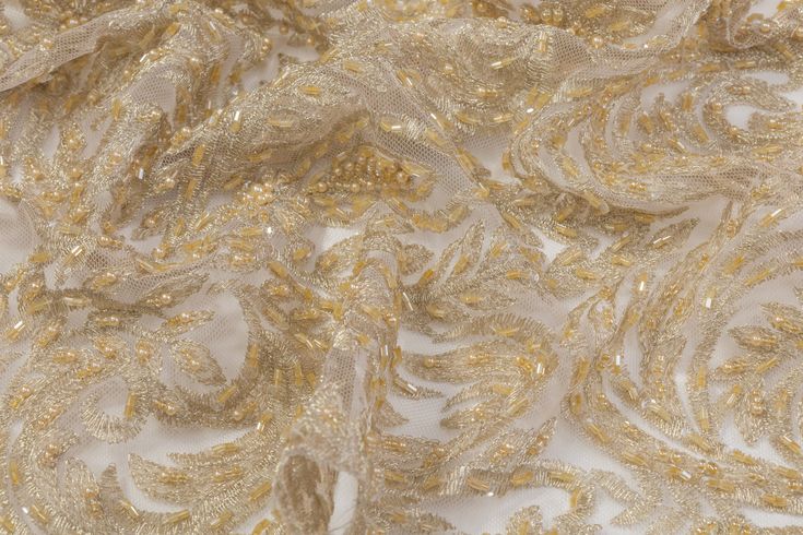 Champagne gold beads and embroidery on a champagne gold tulle. Elegant Pearl Embroidered Fabric For Reception, Elegant Embroidered Fabric With Pearl Embroidery For Reception, Elegant White Embroidered Fabric For Celebrations, Elegant Beige Embroidered Fabric, Elegant Pearl Embroidered Fabric For Celebration, Gold Embellished Organza For Embroidered Fabric, Gold Embellished Embroidered Organza Fabric, Elegant Festive Embroidered Organza Fabric, Elegant Beige Embroidered Fabric For Formal Occasion