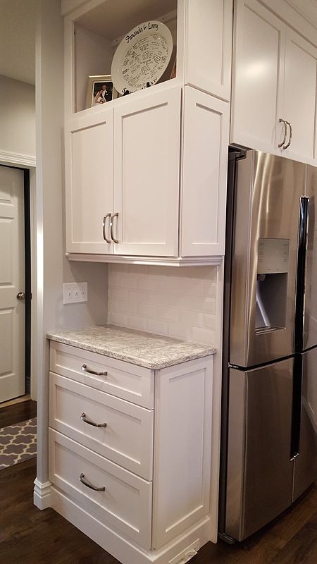 a stainless steel refrigerator freezer sitting next to a white kitchen cabinet with marble counter tops