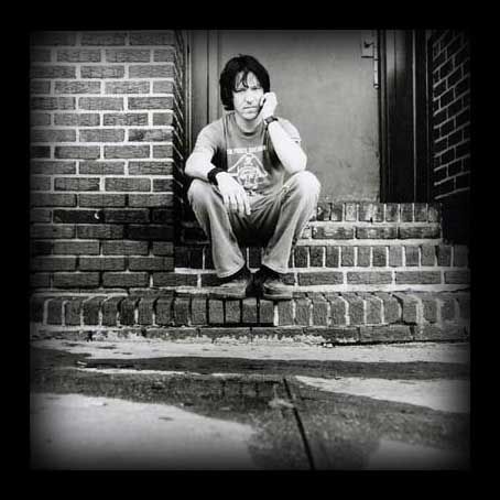 black and white photograph of a man sitting on the steps with his hands to his face