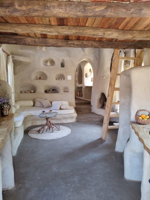 a living room filled with lots of furniture and walls covered in white stucco, next to a fire place