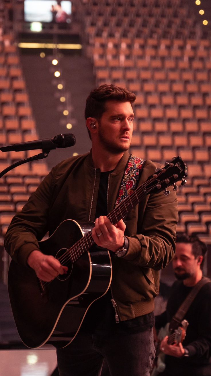 a man holding a guitar while standing in front of a microphone