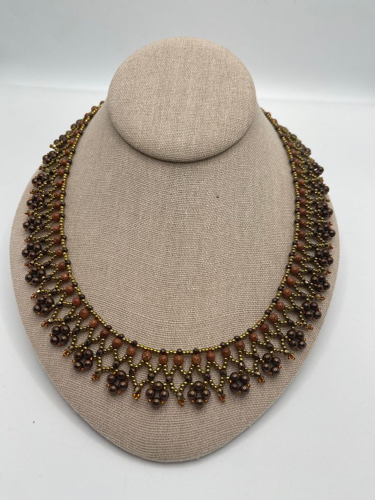 This handmade woven women's necklace is 18.5 inches and made with glass bronze and rust colored round beads. It is embellished with crystals and various seed beads. It closes with a gold plated toggle clasp. It is lightweight and can easily be worn with casual or formal occasions. Adjustable Brown Beaded Round Necklace, Adjustable Brown Beaded Necklace, Adjustable Brown Round Beaded Necklace, Adjustable Round Brown Beaded Necklace, Adjustable Gold Beaded Necklaces With Bead Caps, Brown Beaded Necklaces With Tiny Beads, Brown Beaded Necklace With Tiny Round Beads, Brown Czech Glass Beaded Chain Jewelry, Brown Czech Glass Jewelry With Beaded Chain