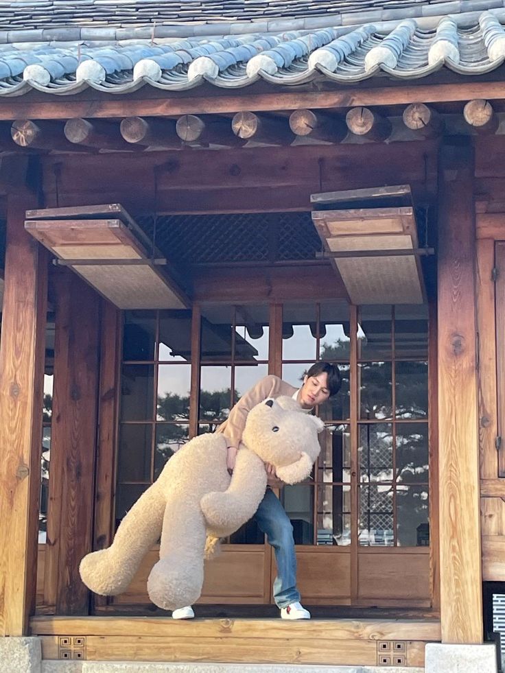 a man holding a large stuffed animal in front of a building