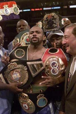 two men standing next to each other in front of a crowd holding up their belts