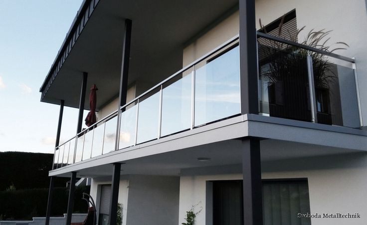 a person standing on the balcony of a white building with black railings and balconies