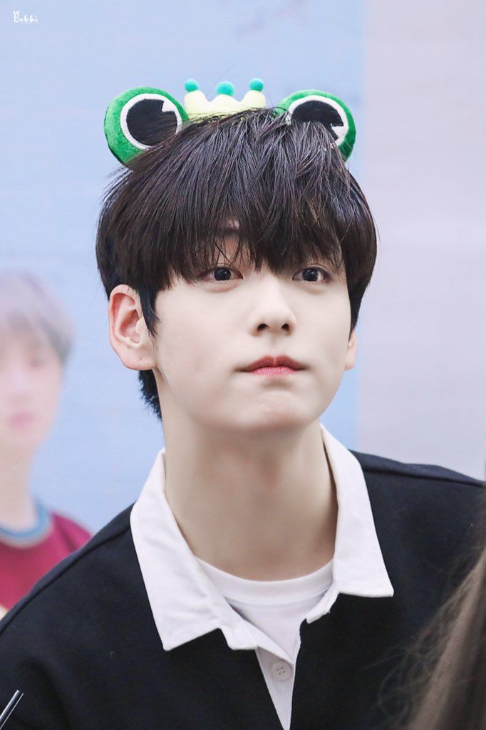 a young man with black hair wearing a green frog ears headband and white shirt