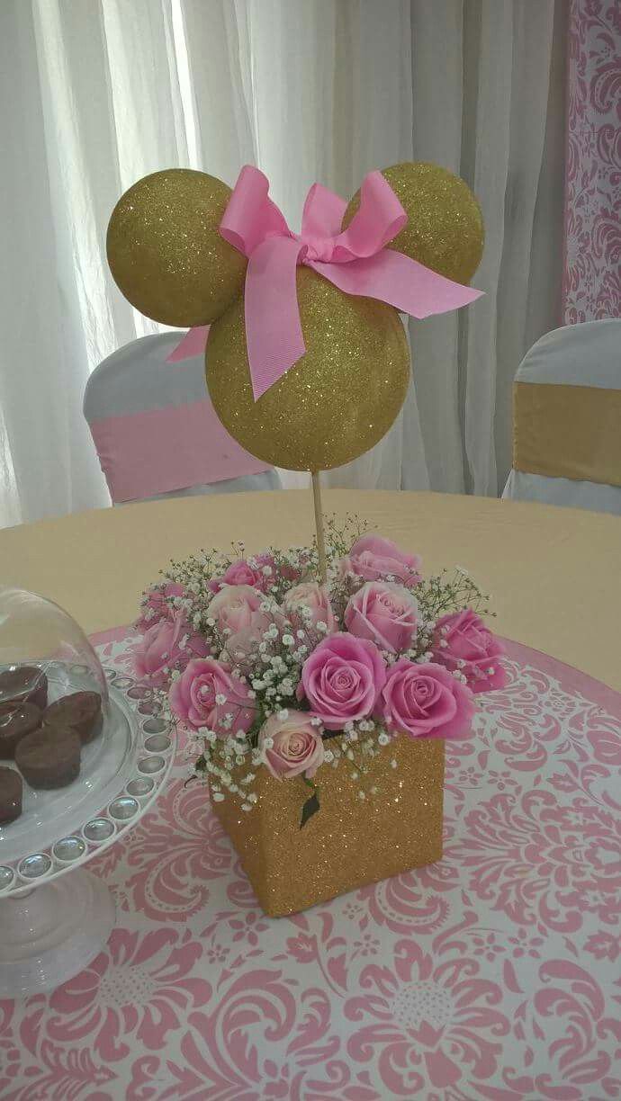 a table topped with a vase filled with pink flowers and minnie mouse ears on top of it