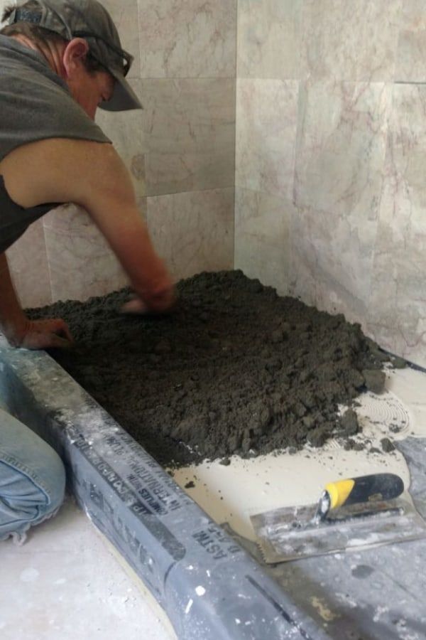 a man working on cement in a bathroom