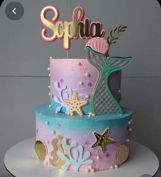 there is a pink and blue cake with mermaid decorations on the top that says sophia