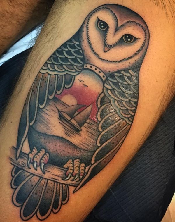 an owl tattoo on the leg with a boat in it's beak and clouds