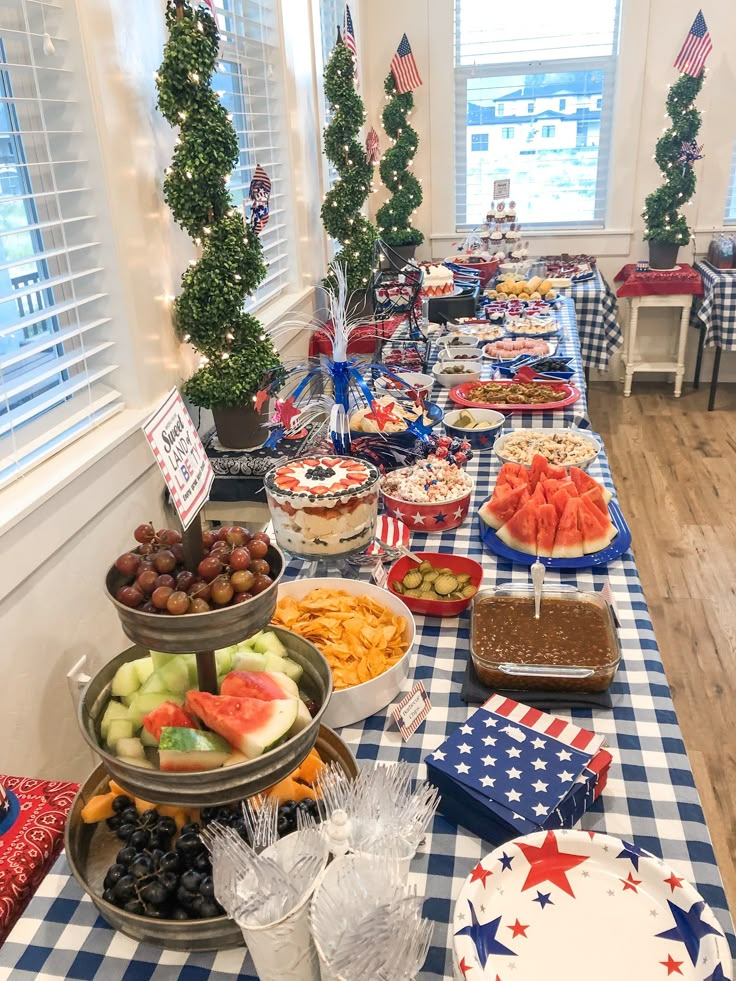 a long table filled with lots of food on top of a blue and white checkered table cloth