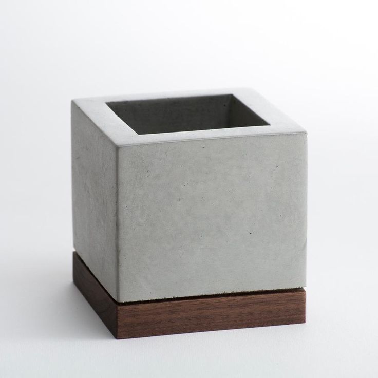 a white square vase sitting on top of a wooden stand in front of a white wall