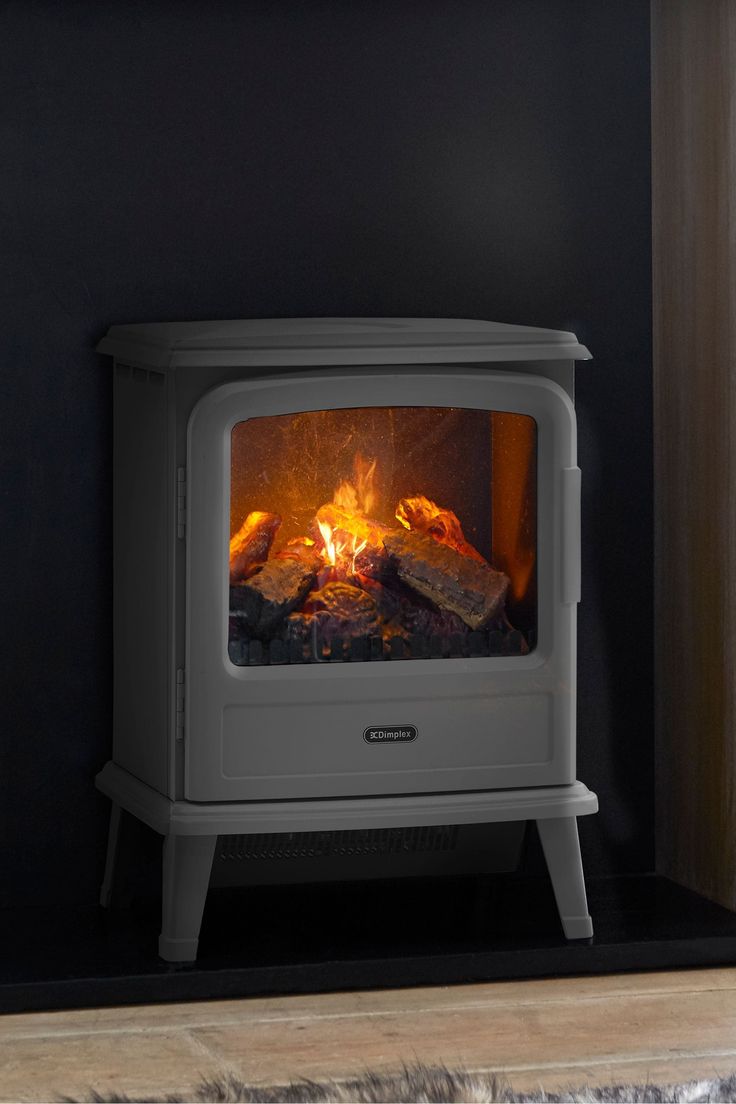 a white stove with logs burning in it