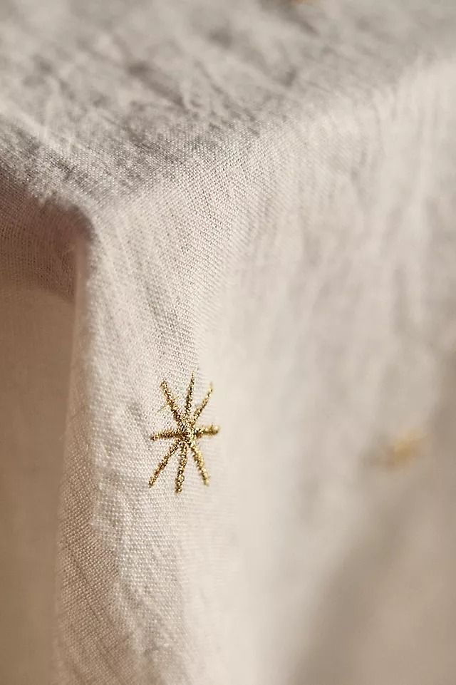 a white table cloth with a gold embroidered star on it