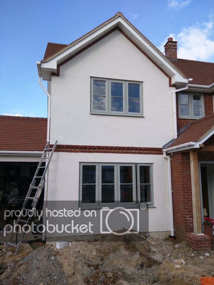 a house being built with a ladder in front of it and some windows on the side