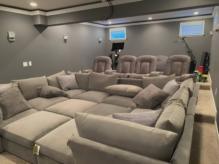 a large sectional couch sitting in the middle of a room with two recliners