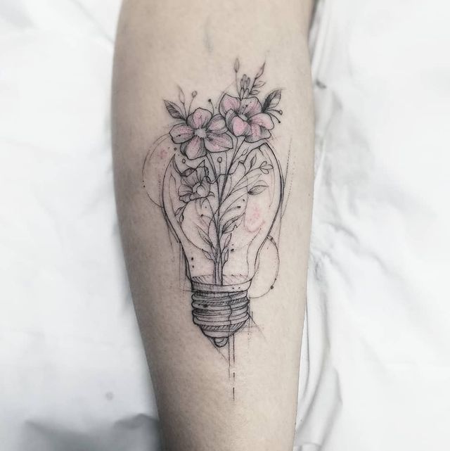 a tattoo on the leg of a person with flowers in a light bulb