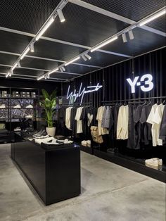 the inside of a men's clothing store with clothes hanging on racks and lighting