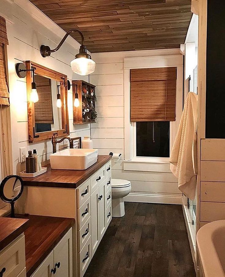 a bathroom with wooden floors and white walls, along with two sinks on the counter