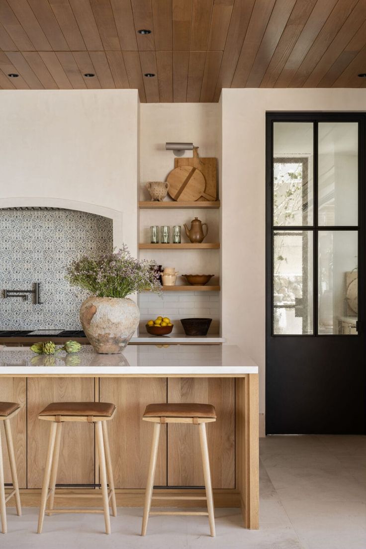 a kitchen with two stools next to an island