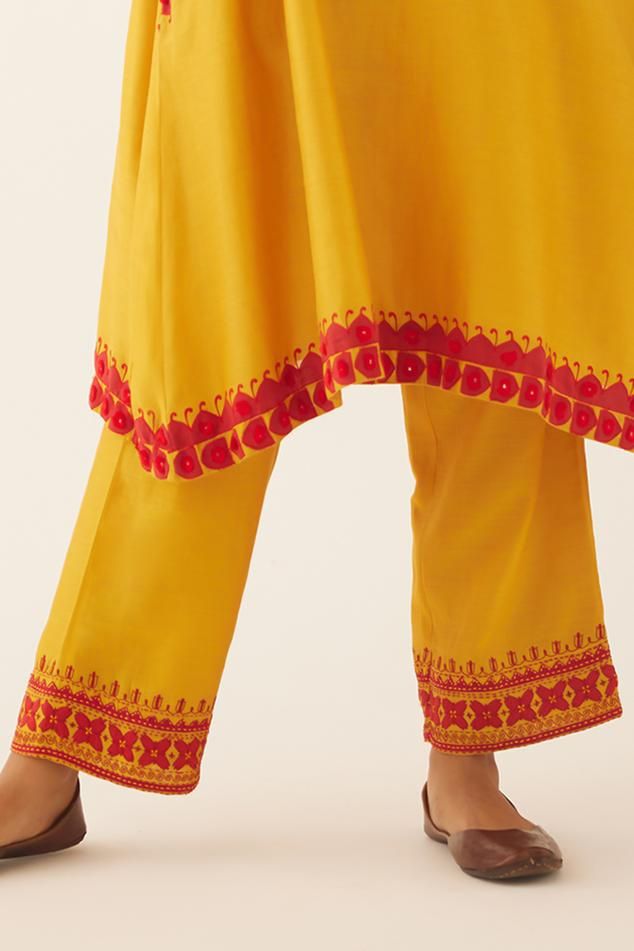 Golden yellow silk chanderi A-line kurta with contrast red floral applique and tassel, sequin embroidery on neckline and sleeve hem. Paired with red applique and kantha embroidered straight pant on hem and braided thread embroidered cotton chanderi dupatta.
Components: 3
Pattern: Embroidery
Type Of Work: Floral applique, tassel, sequin, kantha, thread
Neckline: Notched
Sleeve Type: Three quarter
Fabric: Kurta and Pant: Silk Chanderi, Dupatta: Cotton Chanderi
Color: Gold,Yellow
Other Details: 
At Yellow Traditional Wear With Printed Motifs In Mulmul, Resham Embroidered Anarkali Set For Puja, Embroidered Anarkali Palazzo Set For Puja, Traditional Salwar Kameez With Embroidered Border For Summer, Yellow Palazzo Set With Printed Motifs In Traditional Drape, Yellow Chanderi Palazzo Set With Printed Motifs, Yellow Mulmul Palazzo Set With Zari Work, Traditional Summer Sharara With Embroidered Border, Chanderi Anarkali Set For Puja