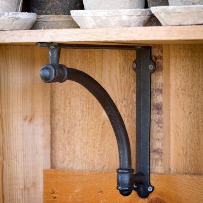 an old fashioned shelf with pots and bowls on it's hooks, hanging from the wall