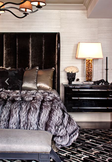 a bedroom with a black bed, white walls and a chandelier hanging from the ceiling