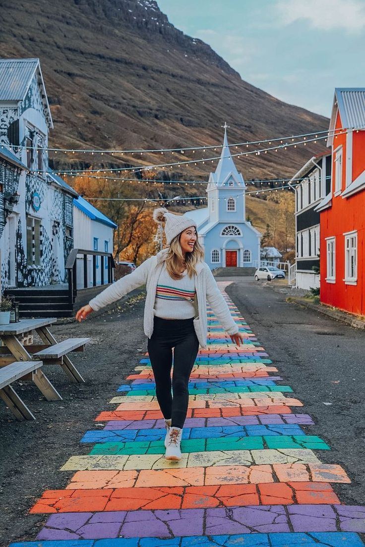 a woman walking across a rainbow painted street