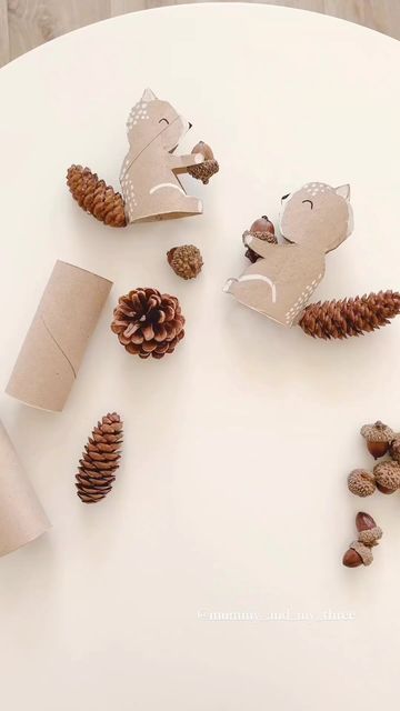 some pine cones are sitting on a table next to small animals and other items that have been made out of toilet paper