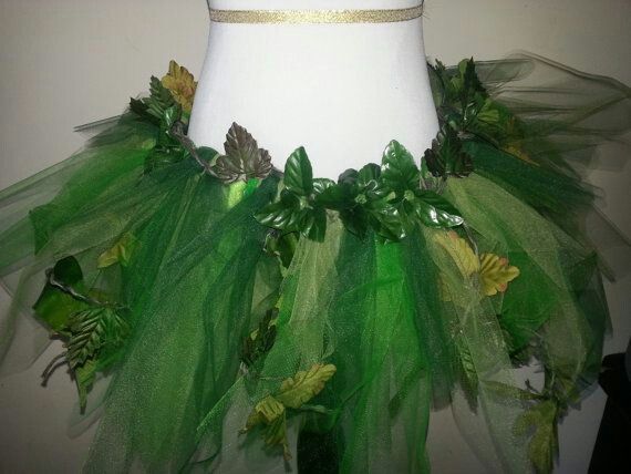 a white mannequin with green tulle and leaves on it's skirt