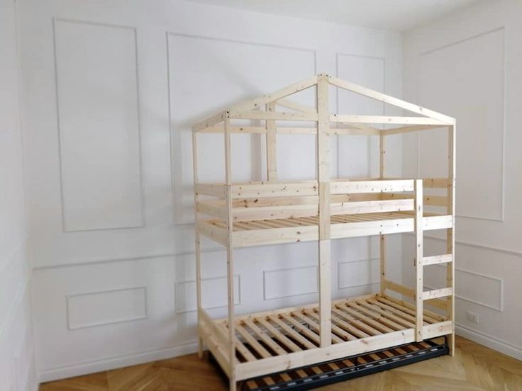 a wooden bunk bed sitting on top of a hard wood floor next to a white wall